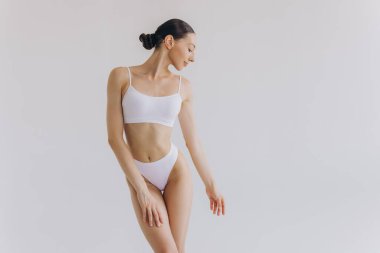 İnce vücutlu güzel bir kadının portresi. Beyaz stüdyo arka planında fotokopi alanı ile poz veriyor.