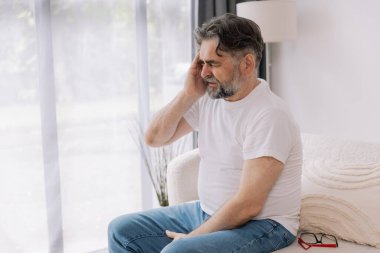 Ev, son sınıf öğrencisi ve stres, duygusal çatışma ve geçici baş dönmesi için kanepede baş ağrısı. Oturma odası, kanepe ve evde emeklilikten doğan acı, migren ve endişe içinde yaşlı bir adam.