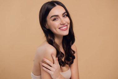 Güzel, genç, esmer, bej arkaplan, yüz bakımı, kozmetik, güzellik ve kaplıca, gülümseyen kadın portresi..