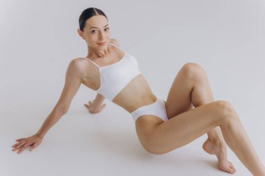 Formda ve güzel bir kadın ve mükemmel bir fiziği var. Yerde beyaz iç çamaşırlı bir kız var. Sağlıklı yaşam tarzı, spor, sağlık, beslenme ve diyet konsepti