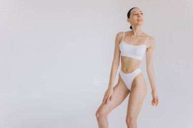 İnce vücutlu güzel bir kadının portresi. Beyaz stüdyo arka planında fotokopi alanı ile poz veriyor.