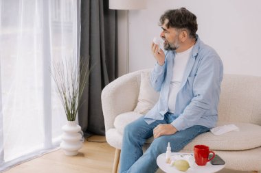 Yaşlı bir adamın mendile hapşırması, soğuk algınlığı veya alerjiden rahatsızlık duyması, mevsimsel alerjiler, virüs, grip ve hasta sağlığı, sağlık durumu, kıdemli bakım ve solunum için tıbbi tedavi