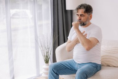 Hasta, öksürük ve kanepede yatan alerji, grip ya da soğuk algınlığı olan yaşlı bir adam. Hastalık, göğüs ağrısı ve astım, enfeksiyon ve COVID 19 virüsü olan yaşlı bir kişi.