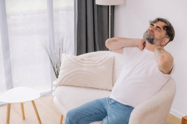 Üst sınıflardan biri içeride oturuyor, boynu ağrıyormuş gibi görünüyor. Üzüntülü bir ifadeyle boynunu tutuyor. Rahatsızlığını gösteriyor. Reklamınız için fotokopi odası.