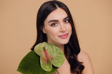 Yüzü ve vücudu yeşil olan genç ve güzel bir kadın. Cilt bakımı güzellik tedavisi konsepti. Yeşil izinli kapanış kızı. Stüdyoda bej arka planda poz veren beyaz bir model.