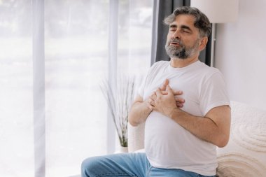 Kalp krizi, kalp krizi. Memnuniyetsiz orta yaşlı adam göğüs ağrısı çekiyor kalp krizi geçiriyor evde sağlık sorunları var. Yaşlı büyükbaba göğsüne dokunuyor ve damar tıkanıklığı yaşıyor.