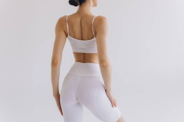 Kadın spor giyim. Damgalamak için kıyafet. Aktif yaşam tarzı. Spor kıyafeti. Mükemmel kalçalı, ince vücutlu, siyah logolu bayan sporcunun arka planı.