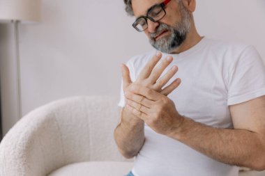 Artrit belirtilerine yakın çekim. Gözlüklü yaşlı adam evde acı çekiyor.
