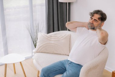 Üst sınıflardan biri içeride oturuyor, boynu ağrıyormuş gibi görünüyor. Üzüntülü bir ifadeyle boynunu tutuyor. Rahatsızlığını gösteriyor. Reklamınız için fotokopi odası.