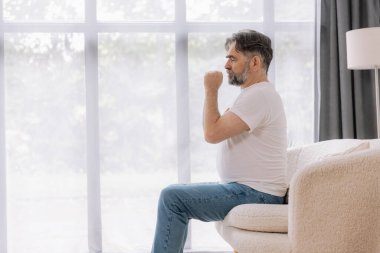 Hasta, öksürük ve kanepede yatan alerji, grip ya da soğuk algınlığı olan yaşlı bir adam. Hastalık, göğüs ağrısı ve astım, enfeksiyon ve COVID 19 virüsü olan yaşlı bir kişi.