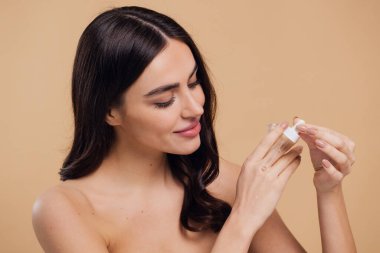 Bej arka planda Serum Bırakan Kadın. Pipette 'ten Serum Kolajeni Nemlendirici kullanan Avrupalı Kız. Yakın plan. Pozitif Gülen Güzel Kadın Portresi. Yüz Cildi Bakımı Konsepti