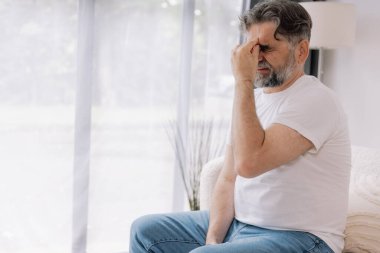 Ev, son sınıf öğrencisi ve stres, duygusal çatışma ve geçici baş dönmesi için kanepede baş ağrısı. Oturma odası, kanepe ve evde emeklilikten doğan acı, migren ve endişe içinde yaşlı bir adam.