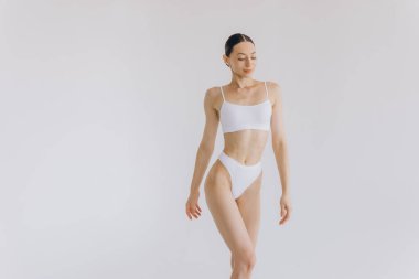 İnce vücutlu güzel bir kadının portresi. Beyaz stüdyo arka planında fotokopi alanı ile poz veriyor.