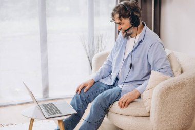 Dedem dizüstü bilgisayar ve kulaklık kullanıyormuş. Koltukta oturuyormuş. Evden çalışan kıdemli adam, çevrimiçi toplantı, görüntülü konuşma, kopyalama alanı