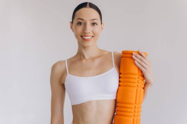 Beyaz spor giysili güzel, ince kadın spor kıyafetleri içinde, spor salonu için turuncu köpük silindirli, fotokopi alanlı beyaz poz veren, sağlığını ve sağlığını destekleyen,.