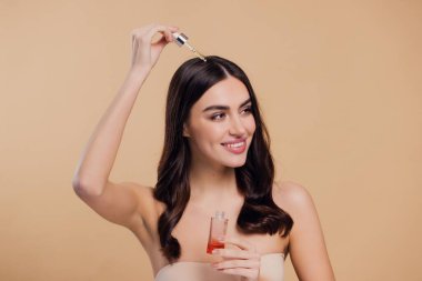 Bej arka planda saç köklerine gerekli yağı uygulayan mutlu genç kadının güzel portresi, metin için boşluk