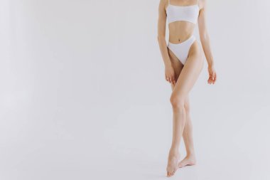 Manzarayı kapat. Beyaz stüdyo arka planında iç çamaşırlı, ince vücutlu güzel bir kadın.. 
