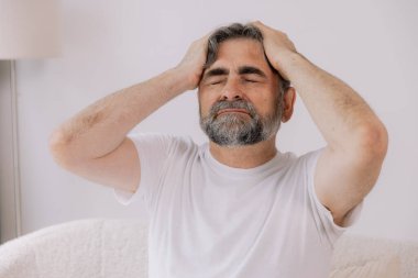 Ev, son sınıf öğrencisi ve stres, duygusal çatışma ve geçici baş dönmesi için kanepede baş ağrısı. Oturma odası, kanepe ve evde emeklilikten doğan acı, migren ve endişe içinde yaşlı bir adam.