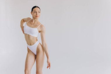 İnce vücutlu güzel bir kadının portresi. Beyaz stüdyo arka planında fotokopi alanı ile poz veriyor.