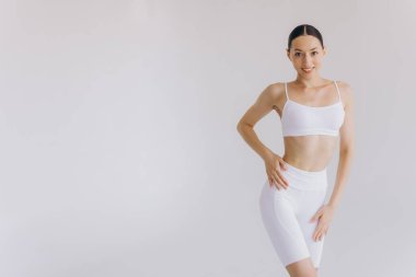 Zayıf vücutlu genç bir kadın yoga yapıyor. Beyaz arka planda izole edilmiş bir şekilde. Vücut ve zihinsel gelişim arasındaki sağlıklı yaşam ve doğal denge kavramı.