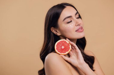 Göz Cildi Bakıcı Kadın. Greyfurt Tutan Güzel Genç Kadın Göz Altındaki Cilde Göz Kremi Döküyor. Antiyaj Tedavisi Konsepti. Yüksek Kalite