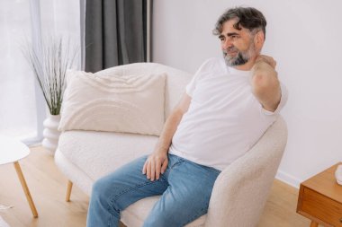 Üst sınıflardan biri içeride oturuyor, boynu ağrıyormuş gibi görünüyor. Üzüntülü bir ifadeyle boynunu tutuyor. Rahatsızlığını gösteriyor. Reklamınız için fotokopi odası.