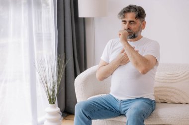 Hasta, öksürük ve kanepede yatan alerji, grip ya da soğuk algınlığı olan yaşlı bir adam. Hastalık, göğüs ağrısı ve astım, enfeksiyon ve COVID 19 virüsü olan yaşlı bir kişi.