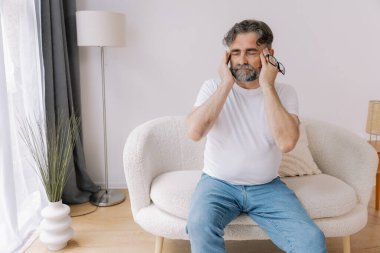 Ev, son sınıf öğrencisi ve stres, duygusal çatışma ve geçici baş dönmesi için kanepede baş ağrısı. Oturma odası, kanepe ve evde emeklilikten doğan acı, migren ve endişe içinde yaşlı bir adam.