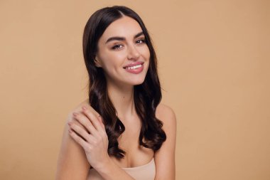Güzel, genç, esmer, bej arkaplan, yüz bakımı, kozmetik, güzellik ve kaplıca, gülümseyen kadın portresi..