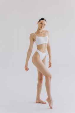 İnce vücutlu güzel bir kadının portresi. Beyaz stüdyo arka planında fotokopi alanı ile poz veriyor.