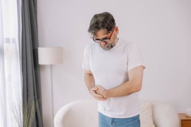 Evde sindirim sorunları, karaciğer ve safra kesesi sorunları ve bağırsak ağrısı çeken yaşlı bir adam var.