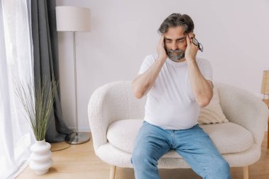 Ev, son sınıf öğrencisi ve stres, duygusal çatışma ve geçici baş dönmesi için kanepede baş ağrısı. Oturma odası, kanepe ve evde emeklilikten doğan acı, migren ve endişe içinde yaşlı bir adam.