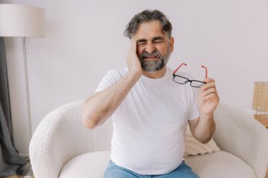 Ev, son sınıf öğrencisi ve stres, duygusal çatışma ve geçici baş dönmesi için kanepede baş ağrısı. Oturma odası, kanepe ve evde emeklilikten doğan acı, migren ve endişe içinde yaşlı bir adam.