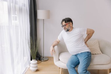 Evdeki kanepede sırt ağrısı çeken son sınıf öğrencisi.