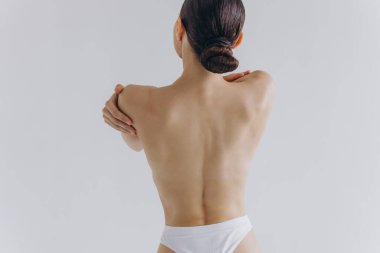 Arkadan kesilmiş, ince vücutlu, mükemmel ciltli, çıplak sütyen giyen seksi kadın beyaz arka planda izole edilmiş kalçalara el ele tutuşuyor. Yaşam tarzı diyet konsepti