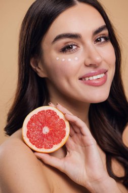 Göz Cildi Bakıcı Kadın. Greyfurt Tutan Güzel Genç Kadın Göz Altındaki Cilde Göz Kremi Döküyor. Antiyaj Tedavisi Konsepti. Yüksek Kalite