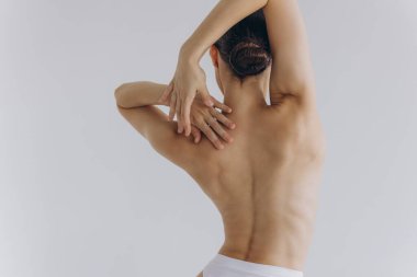 Arkadan kesilmiş, ince vücutlu, mükemmel ciltli, çıplak sütyen giyen seksi kadın beyaz arka planda izole edilmiş kalçalara el ele tutuşuyor. Yaşam tarzı diyet konsepti