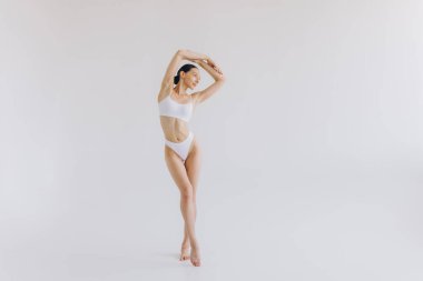 İnce vücutlu, beyaz stüdyo arka planında fotokopi aletiyle poz veren güzel bir kadının tam boy portresi.