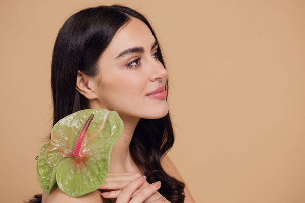 Красота портрет привлекательной молодой обнаженной женщины позирует с цветами изолированы на бежевом фоне студии