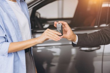 Satıcının ya da müdürün modern kadına araba anahtarlarını verirken yakın plan fotoğrafı. Araba galerisinde yeni araba sahibi.