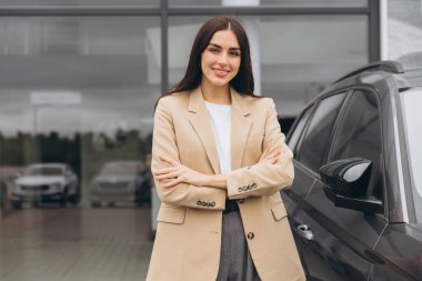 Bej ceketli mutlu kadın müşteri el ele tutuşarak katlanmış araba galerisi galerisi galerisi galerisinde yeni otomobil almak istiyor..