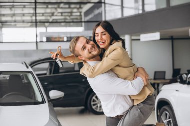 Temsilci olarak yeni otomobilleri olan güzel evli bir çift. Mutlu beyaz adam ve kadın araba aldıktan sonra sarılıyorlar..