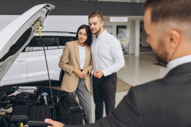 Bir satıcı araba galerisinde beyaz güzel bir çifte kapüşonlu bir araba gösteriyor..