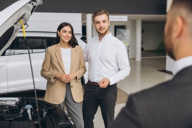 Bir satıcı araba galerisinde beyaz güzel bir çifte kapüşonlu bir araba gösteriyor..