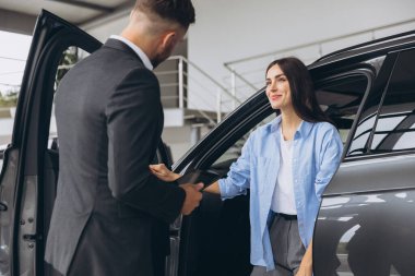 Genç bayan müşteri bayan alıcı, satış elemanı Hold tabletine gömlek danışarak araba galerisi araç galerisi galerisi galerisi araba galerisinde yeni otomobil almak istiyor..