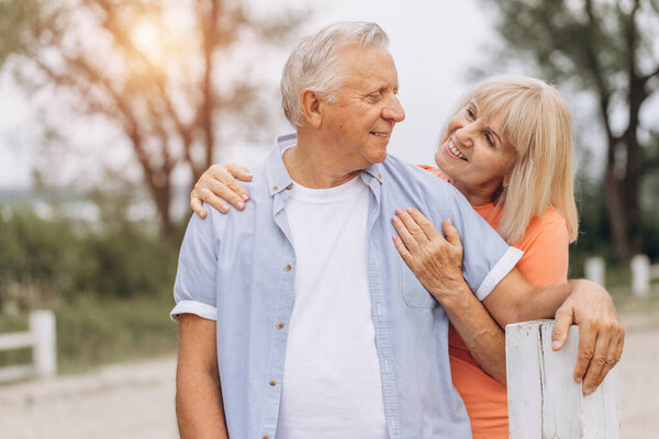 Happy senior couple embracing outdoors, smiling and enjoying time together in a park setting.