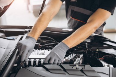 Gri eldivenli, arabanın motorunu ve kaputunu kontrol eden, tanınmayan bir adamın yakın plan fotoğrafı.