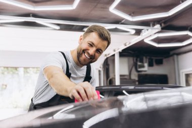 Bir araba ambalaj uzmanı arabaya poliüretan film uygular. Seçici odaklanma. Çip ve çiziklere karşı PPF koruyucu film. Araba ambalajlama.