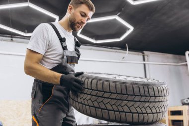Tamirci değiştiren tekerlek, modern arabanın kış ve yaz lastikleri..