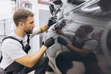 Yan vagon kapısındaki PPF kurulum işlemine yakın. PPF, boyayı çiziklerden ve taş parçalarından koruyan bir boya koruma filmidir. Gardiyan, Koruma, Araba, Yeni, İş.